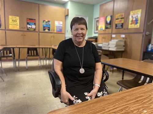 Brenda looks to camera while sitting in her classroom. 